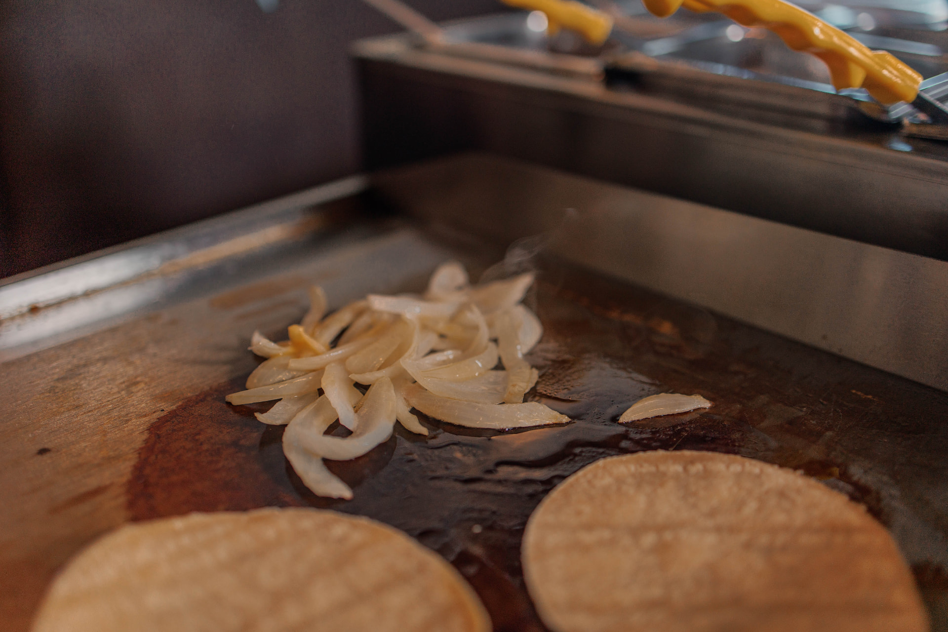 Onions and fresh tortillas on the taco bar griddle